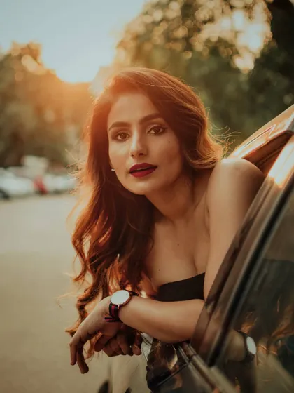 A classic golden hour portrait taken from a car window. The warm light illuminates the subject's face, creating a soft and cinematic shot that feels like a still from a movie.