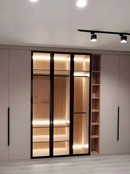 This wardrobe design is a showstopper, combining solid and glass doors with internal lighting. The central glass display is perfect for showcasing your favorite accessories, while the side cabinets offer ample concealed storage.