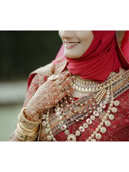 A beautiful shot focusing on the bride's smile and the intricate details of her jewelry and henna-adorned hand.