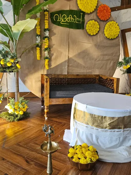 This angled view highlights the different elements of our rustic Valaikappu decor. You can see the traditional brass lamp, the bowls of marigolds, and the floral arrangements that all come together to create a cohesive and celebratory space.