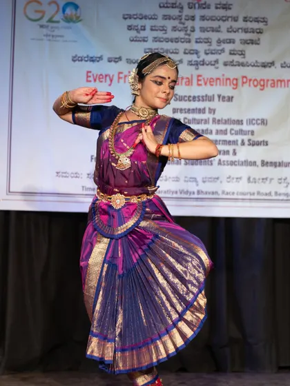 A full-length view of the dancer on stage, showing the beautiful drape of the traditional costume and the confident stage presence we cultivate in our students.