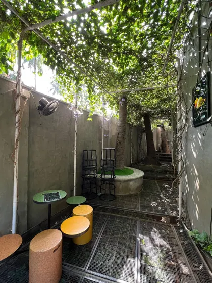 This view shows the different zones within the small garden, including seating nooks and a central planter around an existing tree. The design makes efficient use of every square foot to create a varied experience.