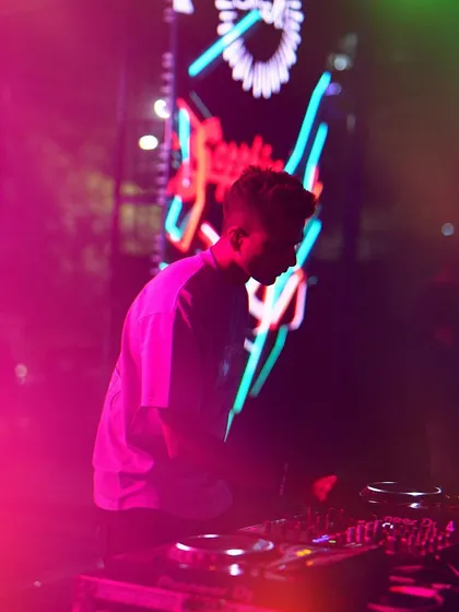 One show at a time. A moody shot of me at the decks during Cul-Ah, the Mount Carmel College fest, with neon lights in the background.