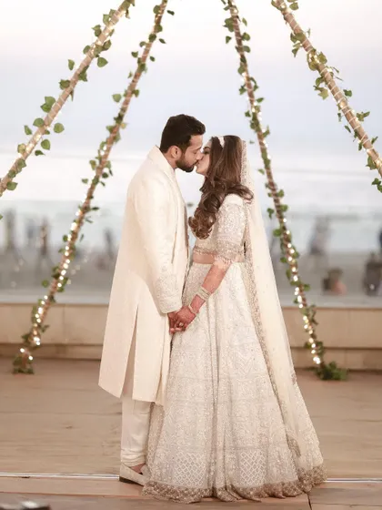 A classic wedding kiss at the altar, set against the beautiful backdrop of the sea. A perfect moment from a beachside Nikaah ceremony.