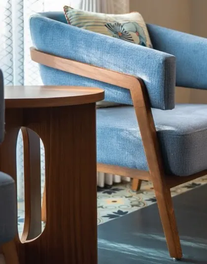 A pair of custom armchairs in a soft blue fabric provide a cozy seating area by the window in this Goan bedroom. The exposed wood frame adds a touch of natural elegance.