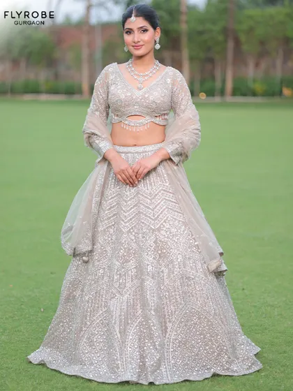 A modern and chic take on the lehenga. This silver-grey creation with a stylish cut-out blouse is perfect for a reception or cocktail party.
