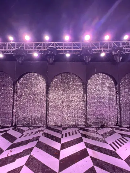 A Bollywood-style sangeet stage with a glittering arched backdrop and a custom marquee sign.