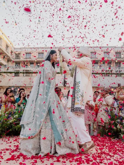 A spectacular Varmala moment, with the couple showered in a sea of red rose petals. The grandeur and joy of this tradition are captured in this stunning wide shot.
