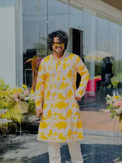 Rocking a yellow and white tie-dye kurta for a Haldi ceremony, ready to get the party started with some festive tunes.