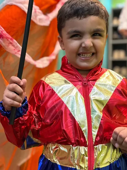 This young superhero in a shiny red, gold, and blue costume is showing off his powerful grin. He's ready to take on any challenge.