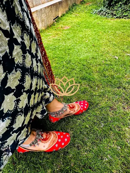 A creative shot of the bride's feet, showing off the beautiful henna stain and her traditional red juttis.