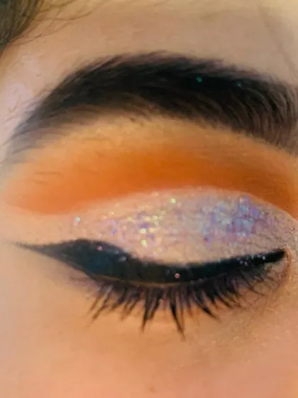 A close-up of a full cut-crease eye makeup look with iridescent glitter.