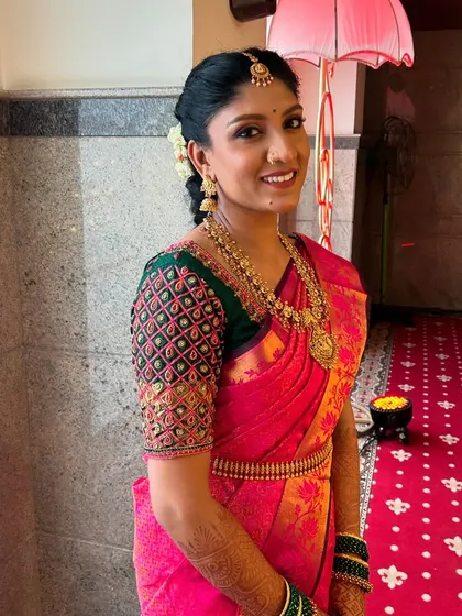 A full-length view of the bride's stunning look. The makeup was carefully balanced to complement her vibrant pink Kanjeevaram saree and the detailed embroidery on her blouse.
