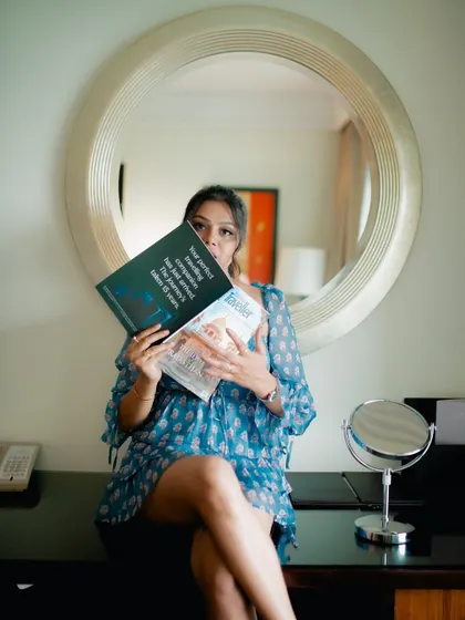 A creative indoor portrait of a model sitting at a vanity, partially hiding behind a magazine. This shot is playful and tells a story.