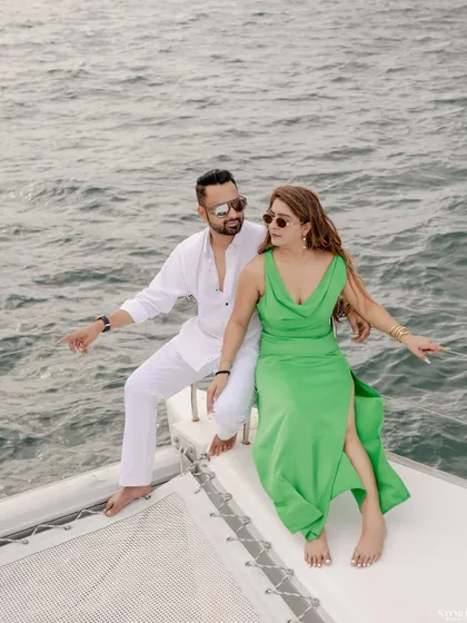 A dynamic shot of the couple on the front of a yacht, with the ocean spray and wind creating a sense of adventure and freedom.