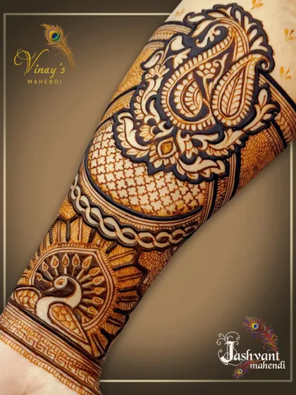 A close-up of the forearm detail from the groom's sister's mehndi, showcasing a peacock and a large paisley motif.