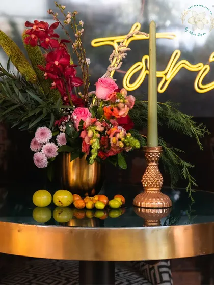 A floral centerpiece with a neon sign in the background. This image captures the blend of modern and classic elements we often use to create a unique sundowner vibe.