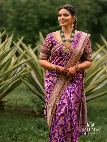 This bride is wearing a magnificent purple Banarasi silk saree. The blouse is intricately hand-embroidered to match the saree's rich pattern.