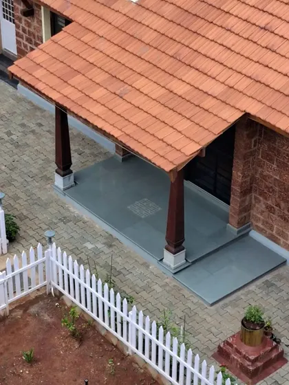 The front sit-out of the Basavanagudi house is a perfect spot to enjoy the morning sun or play a game of 'Chaukabara'. The space is defined by traditional wooden pillars and a cool stone floor, inviting connection with the outdoors.