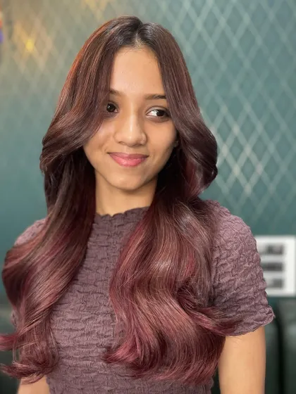 Red hues for a change. This client is rocking a beautiful shade of red with soft waves and face-framing layers that make the color pop.