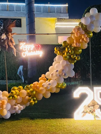 This shot shows the anniversary setup at dusk, with the neon sign and marquee number glowing beautifully in the garden setting.