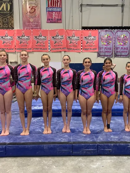 The Xcel team stands in formation, showcasing their unity and matching leotards before the competition begins.