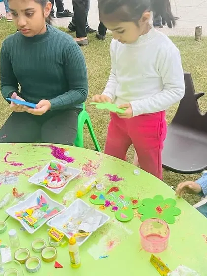 Art is a wonderful activity for all ages. Here, older and younger children work side-by-side at a craft table, sharing materials and ideas in a collaborative and creative environment.