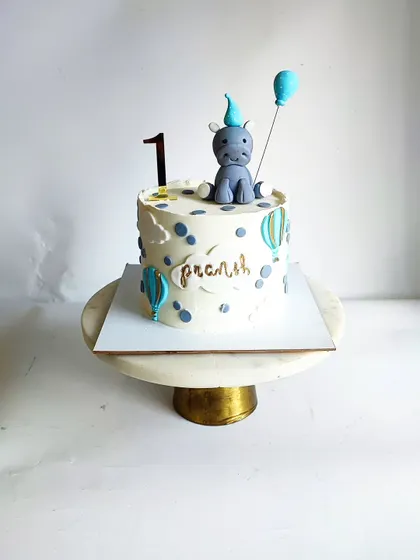 The hippo-themed first birthday cake, decorated with hot air balloons and a personalized nameplate.