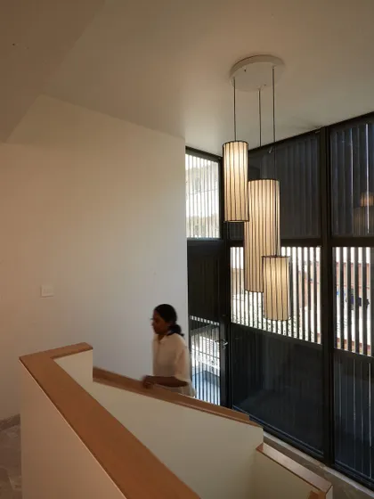 A cascading pendant light fixture illuminates the stairwell, adding another layer of sculptural beauty to the space.