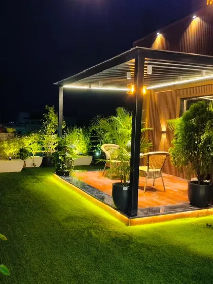 A completed pergola with a wooden deck in Model Town, surrounded by lush greenery and ambient lighting.