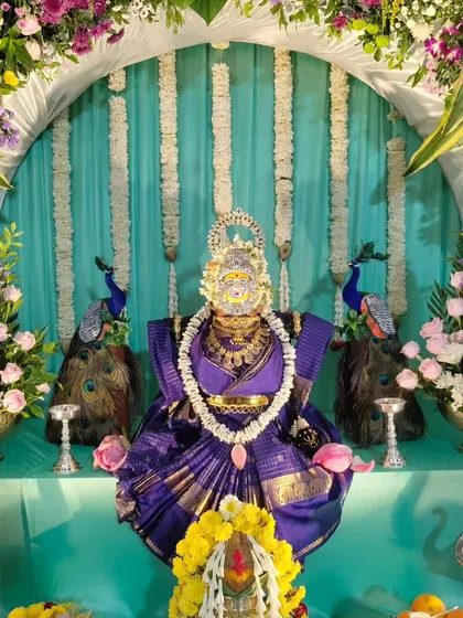 A close-up of the Varamahalakshmi idol and the surrounding floral decor.