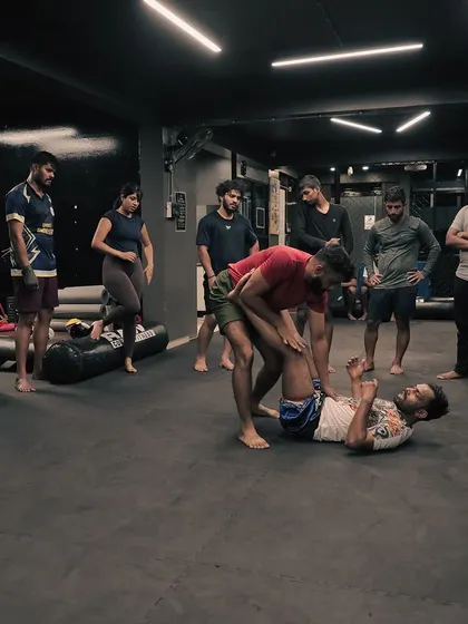 A group of students watch intently as I demonstrate a grappling technique on the mat.