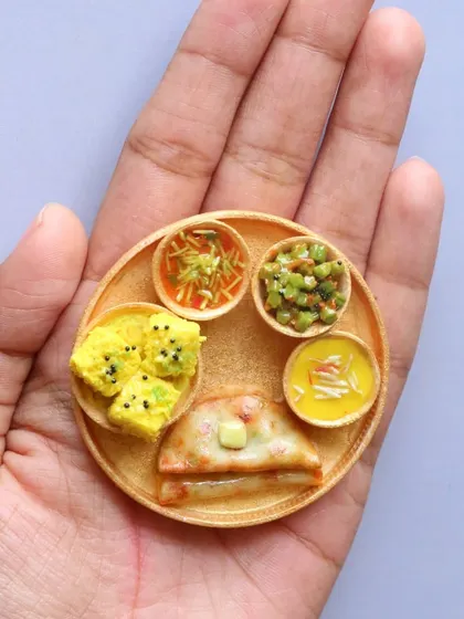 A Kathiawadi thali held in the palm, showcasing the unique dishes of the region.