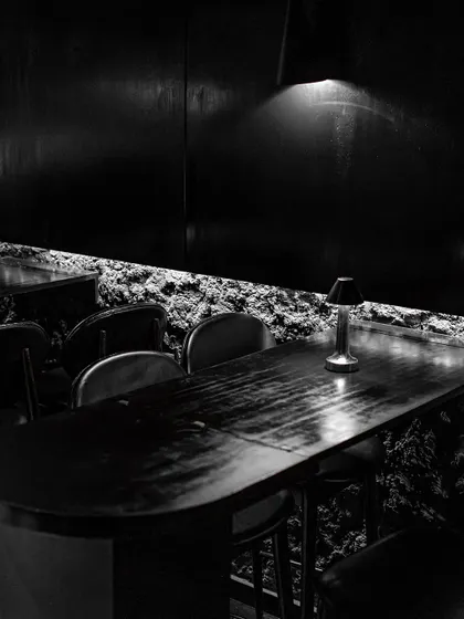 Dine in the mystique of a minimalist, modern-day den. The combination of raw, cave-like walls and sleek, dark furniture creates a uniquely sophisticated dining environment.