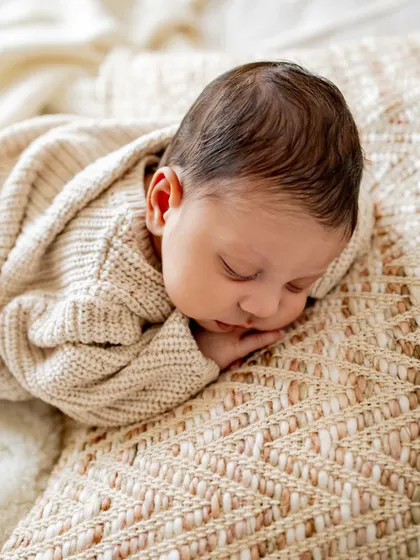 A newborn sleeping peacefully on a comfy bed. Lifestyle sessions are perfect for capturing these serene moments in a natural, unposed way.