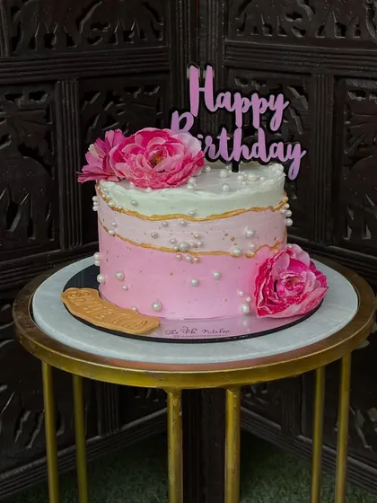 A beautiful pink ombré cake with delicate edible pearls and fresh peonies. The gradual color transition gives it a soft and elegant feel.