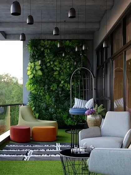 This spacious balcony uses a large, succulent-filled living wall as its main feature. The design includes varied seating options like a hanging chair and modern armchairs, all arranged on soft artificial grass to create a comfortable and stylish outdoor lounge.