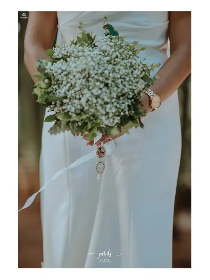 The bride's bouquet of baby's breath is simple, elegant, and timeless, perfectly complementing her modern wedding dress.