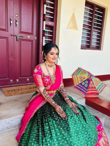 A full-length shot of the bride sitting gracefully, her intricate mehendi visible as a key part of her festive ensemble.