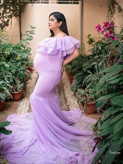 A stunning solo portrait of the mother-to-be in a beautiful lavender gown. The garden setting enhances her natural glow and elegance.