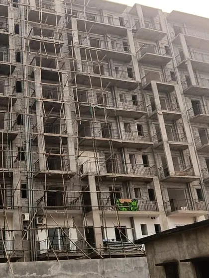 A large residential housing project under construction. The image shows the concrete structure and extensive scaffolding, indicating the scale of the development.