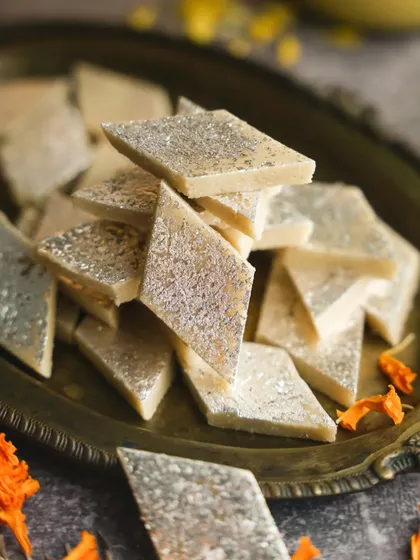 A generous pile of Kaju Katli on a vintage brass plate. The simple, clean styling lets the texture and iconic shape of this Diwali favorite be the hero.