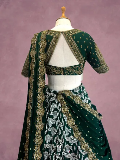 The back design of the emerald green lehenga, featuring a stylish keyhole cutout. The blouse is embroidered with delicate motifs and finished with an elegant border, ensuring the bride looks stunning from every angle.