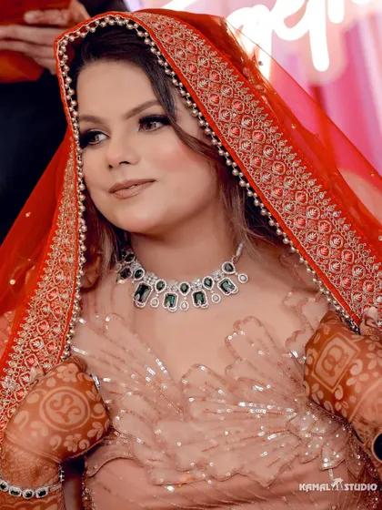 A beautiful close-up of the bride, Jiya, with her dupatta over her head, highlighting her emerald necklace.