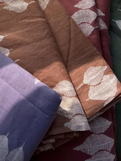 A collection of our printed pure linen fabrics in various earthy and pastel tones, all featuring the same delicate white leaf print.