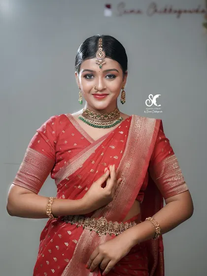 A classic studio portrait for a makeup academy, showcasing a semi-bridal look. The clean lighting and pose highlight the flawless makeup application and traditional jewelry.