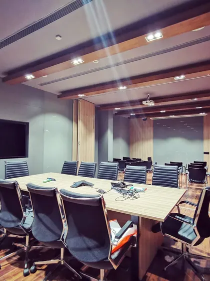 The main conference room, designed for formal meetings and presentations. The space is equipped with full audiovisual capabilities and features wood-paneled accents and comfortable seating for long sessions.