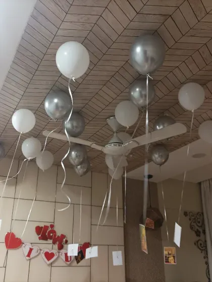 A simple yet personal anniversary decoration. Silver and white balloons float on the ceiling, with photos of the couple hanging from the ribbons.