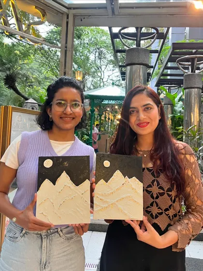 Two friends showing off their matching mountain-themed texture paintings. It's a great activity to do with a loved one.