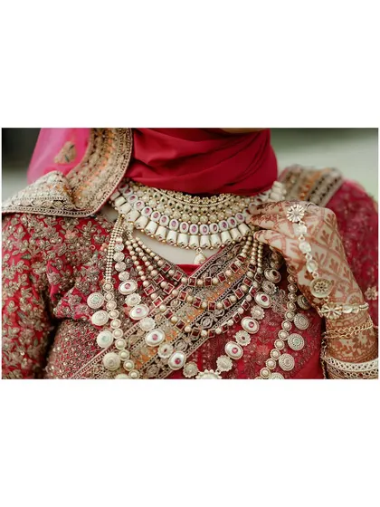 A detailed shot of the bride's opulent necklaces and the fine embroidery of her wedding attire.